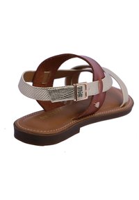 Sandal de cuero marrón que presenta una correa dorada texturizada, una correa de crema lisa y una hebilla metálica. Suela texturizada con acentos de costura blanca.