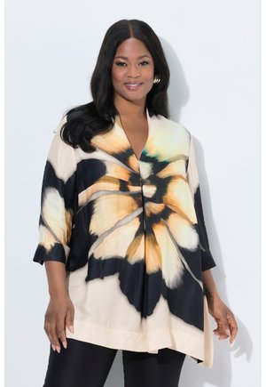 Vloeiende blouse in lichtbeige, met een groot bloemenpatroon in zwart, geel en teal. Driekwartmouwen en een V-halslijn.