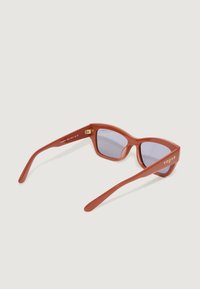 Ochelari de soare roșii din acetat cu ramă unghiulară, lentile colorate în albastru și logo-ul "vogue" de culoare aurie pe braț. Textură netedă și design modern.