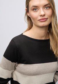Sweter w czarno-beżowe paski z okrąg�łym dekoltem, miękką fakturą i długimi rękawami. Projekt wyróżnia się szerokimi poziomymi paskami.