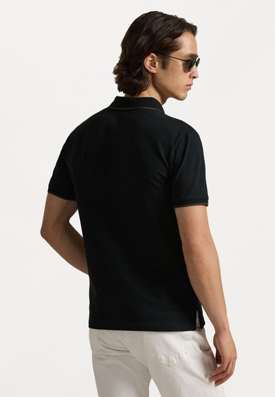 Črna polo majica s slim fit krojem, kratkimi rokavi in zlatimi detajli ob ovratniku. Tkanina izgleda gladka in ima mehak občutek.