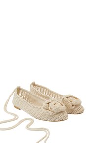 Bailarinas de ganchillo beige con diseño de malla abierta, que presentan un prominente adorno de flor en la puntera y una delgada cinta para asegurar.