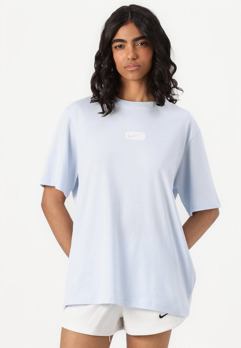 Camiseta de gran tamaño de color azul claro, hecha de algodón, con cuello redondo, mangas cortas y un logo de Nike blanco centrado en el pecho.