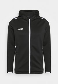 Svart hoodie-jacka med vit dragkedja och "JAKO"-logga. Har textil med struktur, sidofickor och vita detaljer på ärmarna.