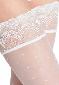 Bas résille blancs avec un haut décoratif à volants, texture transparente à pois, et un design ajusté pour un maintien sécurisé.