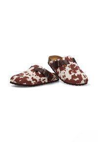 Zuecos con un diseño de estampado de vaca en tonos marrón y blanco, hechos de material suave, con una hebilla decorativa marrón y una suela de goma texturizada.