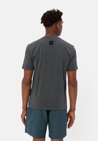 T-shirt à manches courtes pour hommes en tissu gris foncé chiné, avec un petit patch logo noir dans le haut du dos et une coupe décontractée.