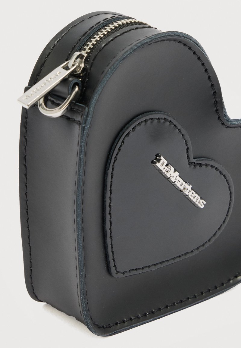 Black leather heart-shaped coin purse with silver zipper and metal logo on front stitched heart patch.