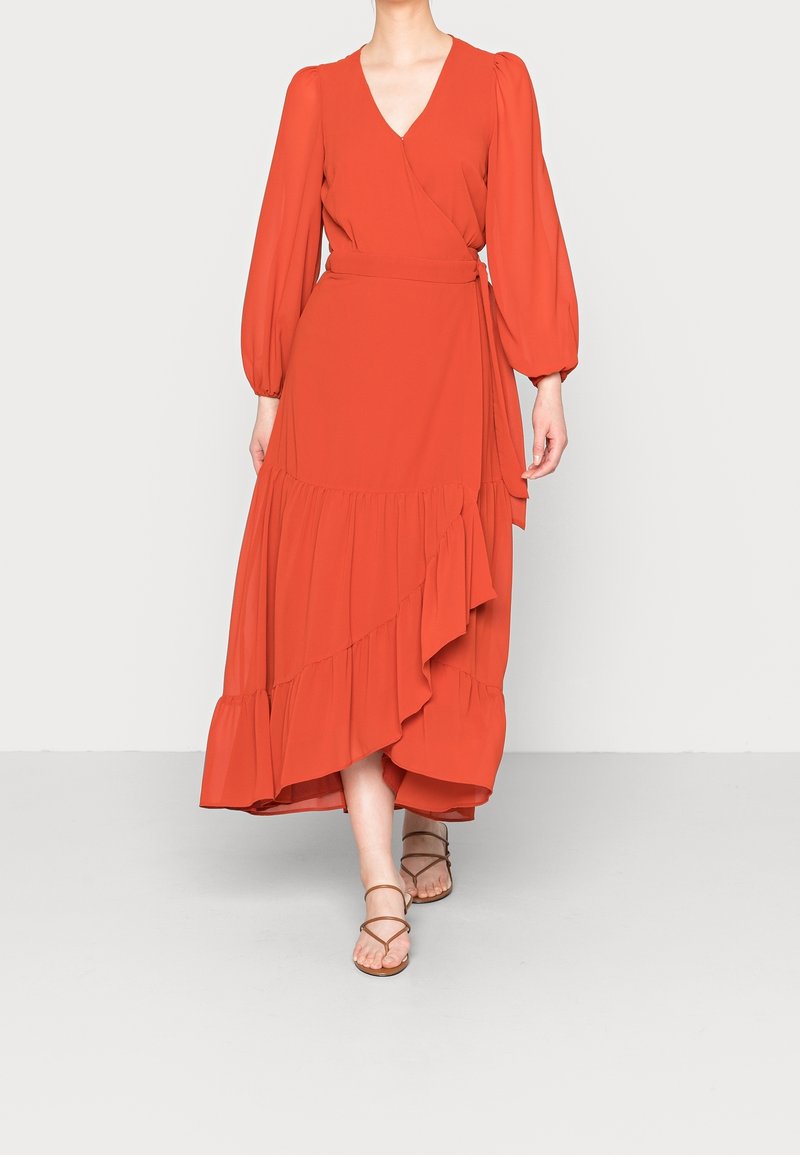 Czerwona sukienka owijana z długimi bufkami, głębokim dekoltem w kształcie V oraz warstwowym detailingiem z falbanek u dołu. Lekki materiał o gładkiej teksturze.