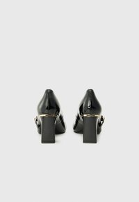 Black patent leather high-heeled shoes with a square shape, chunky heel, and a gold accent band at the back. Smooth texture, no visible patterns.