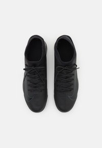 Czarne sportowe buty z teksturowaną powierzchnią, o smukłym designie, okrągłych noskach i sznurówkach. Dyskretne niebieskie akcenty w pobliżu logo.