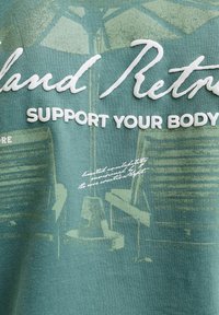 Texte « Soutenez votre corps » sur une illustration estompée d’équipements de gym, y compris des poids et des bancs, sur fond de tissu vert.