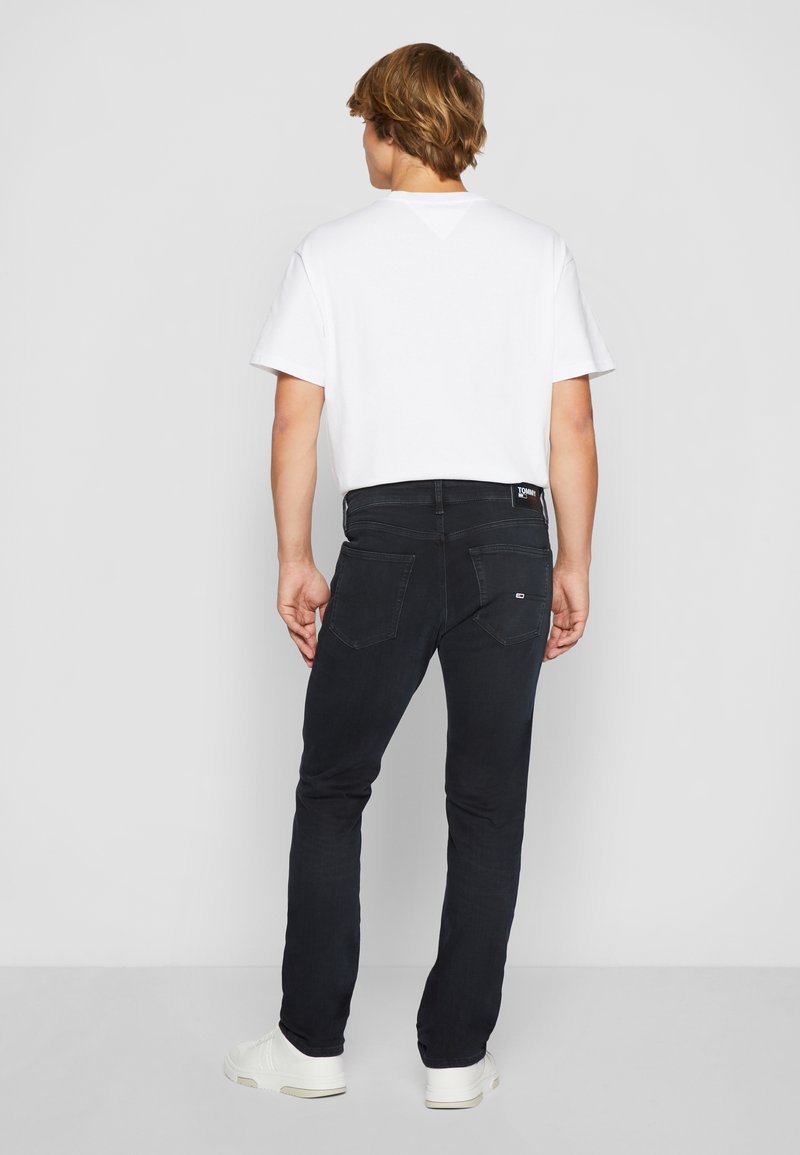 Czarne dżinsy o slim fit, w połączeniu z białą koszulką z bawełny. Godne uwagi cechy to tylne kieszenie oraz metka z logo.