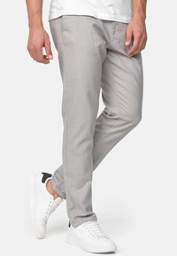 Helle graue Chinos mit geradem Schnitt, aus weichem Material gefertigt. Mit seitlichen Taschen und in Kombination mit weißen Sneakers.