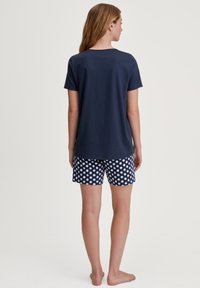 Marineblauwe katoenen t-shirt met korte mouwen, gecombineerd met marineblauwe en witte polka dot shorts, die een comfortabele pasvorm en zachte textuur tonen.