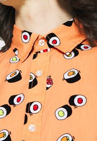 Short-sleeve, orange shirt with sushi-themed pattern, featuring black, white, and red accents; button-up neck with a classic collar.