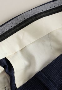 Mornarsko modra tkanina z gladko kremasto podlogo in črno-belim ribjim vzorcem na pasu. Brez vidnih kovinskih delov.