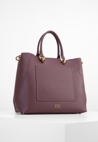 Borsa in pelle mauve con hardware dorato, forma strutturata, manici doppi e tasca a toppa frontale. Logo impresso sul fondo.