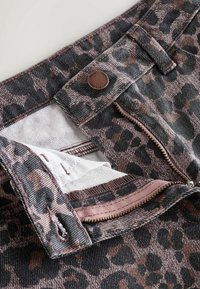 Jeans med leopardprint, der har lynlås, kobberknaplukning og en blød tekstur med afdæmpede lyserøde og grå nuancer.