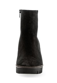 Stivale alla caviglia in suede nero con superficie testurizzata, zip posteriore e suola in gomma nera spessa e rigata. Design semplice e lineare.