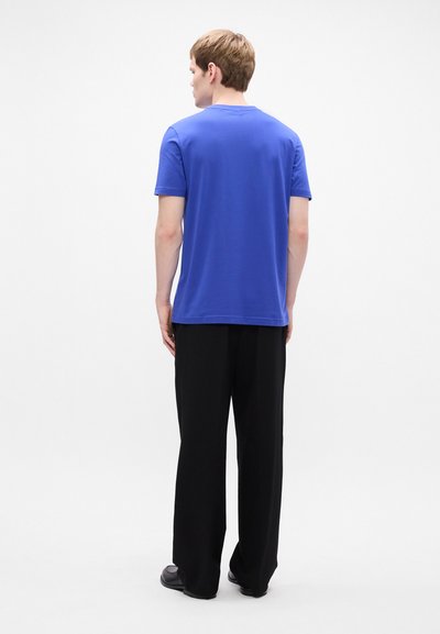 T-shirt bleu à manches courtes avec un col rond, associé à un pantalon large noir. Texture simple et lisse, design ajusté et apparence décontractée.