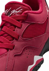 Sneaker rossa con tomaia in rete testurizzata, dettagli in suede e particolari neri. I lacci sono rossi con un motivo stampato sulla linguetta.