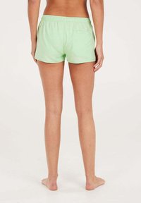 Svetle zelené bavlněné kraťasy s elastickým pasem, se zadní kapsou. Střih nad střední částí stehen, hladká textura, žádné viditelné vzory.