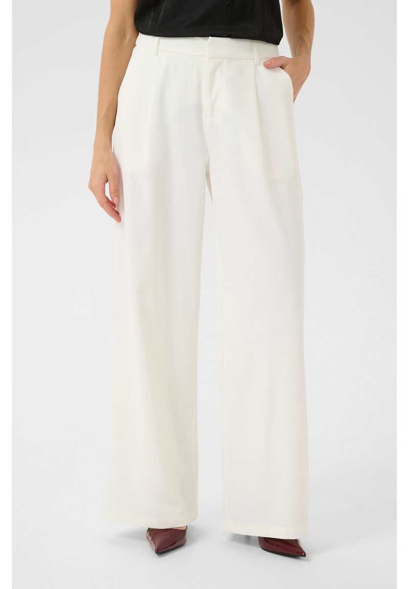 Kalhoty s širokými nohavicemi v světle krémové barvě, vyrobené z hladké látky. Mají záhyby, kapsy po stranách a vypasovaný pas.