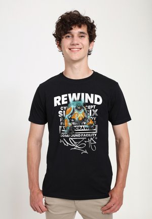 Sort t-shirt med et grafisk design af en farverig robot og fed skrift, der inkluderer "REWIND" og "COMPOUND FACILITY."