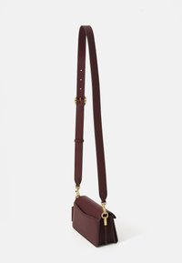 Small burgundy leather crossbody bag with adjustable strap and gold-tone hardware, shown against a plain white background.