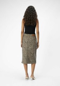 Jupe midi imprimé léopard aux tons naturels, avec une coupe droite, une fente arrière et une étiquette de marque à la taille. Portée avec des mules à talons.