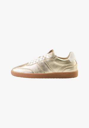Goldene Metallic-Sneaker mit glatter Oberfläche, weißen Akzenten, Schnürung vorne und einer hellbraunen Gummisohle; versehen mit diagonalen Streifen an den Seiten.