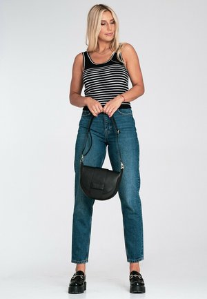 Czarnobiały top na ramiączkach w paski, niebieskie jeansy z wysokim stanem oraz czarna skórzana torba na ramię o zaokrąglonym kształcie i fakturowanym wykończeniu.