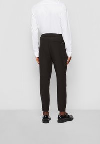 Svarta tapered byxor med resårmidja, som har en bakficka och en diskret logotypdetalj på högra sidan.