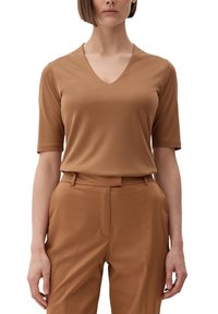 Brun V-hals t-shirt lavet af glat stof, med korte ærmer. Kombineret med matchende brune bukser, hvilket skaber et sammenhængende look.