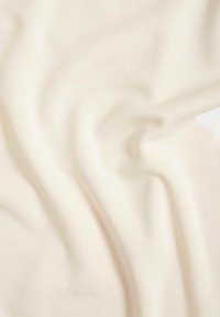 Cremefarbener Stoff mit glatter Textur, der weiche Falten und Kurven aufweist, die ein subtiles Gefühl von Bewegung erzeugen.