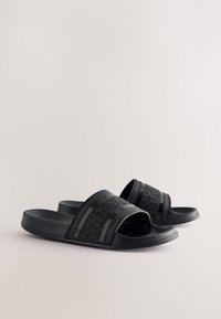 Sandali neri con suola in gomma strutturata, caratterizzati da due ampie fascie con motivi geometrici e una soletta sagomata per il comfort.