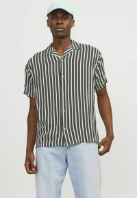 Sort-hvid stribet kortærmet skjorte med krave og knaplukning, parret med lyseblå denimjeans.