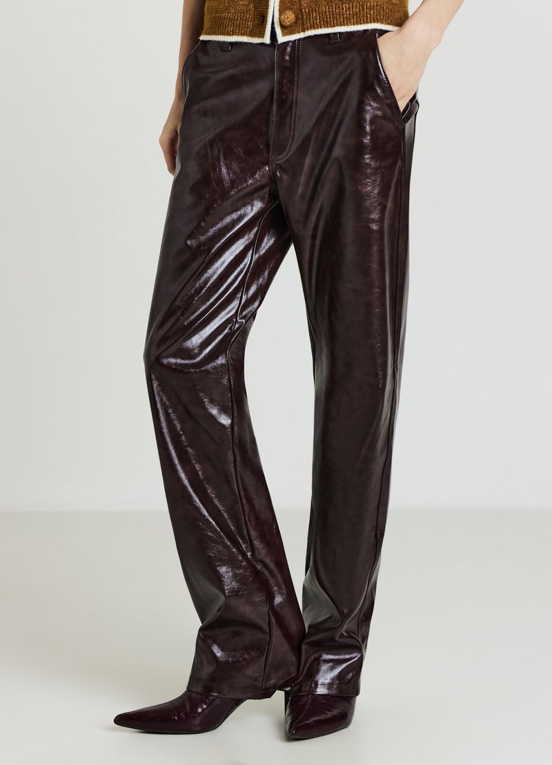 Glänzende, dunkelburgunderrote Lederhose mit lockerem Schnitt. Auffällige Merkmale sind Seitentaschen und eine glatte, glänzende Oberfläche.