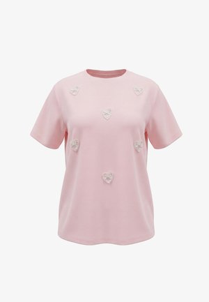T-shirt rose clair à manches courtes avec six petits cœurs en dentelle blanche appliqués de manière uniforme sur le devant.