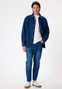 Denim-paita ja siihen sopivat farkut keskipitkä sininen sävy. Valkoinen crewneck-paita alla. Ruskeapohjaiset tennarit. Rentoa tyyliä.