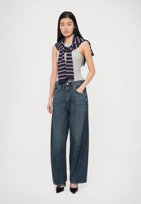 Raiškių tamsiai mėlynų džinsų, pilkos tanktopo ir tamsiai mėlyno dryžuoto megztinio, pririšto aplink kaklą, derinys. Juodi aukštakulniai batai.