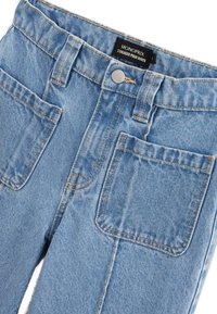 Jean en denim bleu clair avec un design classique à cinq poches, des coutures contrastées visibles et une fermeture à bouton en métal, avec une étiquette de marque.