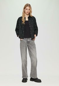 Zwarte overhemd met hartjespatroon, gecombineerd met een zwarte tanktop en grijze wijde jeans. Gekaapt met chunky zwarte laarzen.
