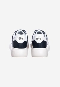 Sneaker navy e bianchi con tomaia in pelle liscia, collare imbottito e etichetta posteriore che riporta "est. 1995". Suola bianca texturizzata.