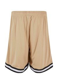Shorts de sport beiges avec une texture en maille, dotés d'accents rayés noir et blanc à l'ourlet et d'une taille élastique.