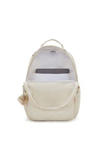 Mochila Kipling de color crema abierta para mostrar el compartimento acolchado para portátil con una tableta dentro y un pequeño llavero de mono de peluche colgando de un lado.