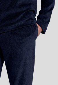 Sudadera azul marino y pantalones de chándal de tela suave, con un bolsillo en los pantalones y un ajuste relajado alrededor de los puños y el dobladillo.