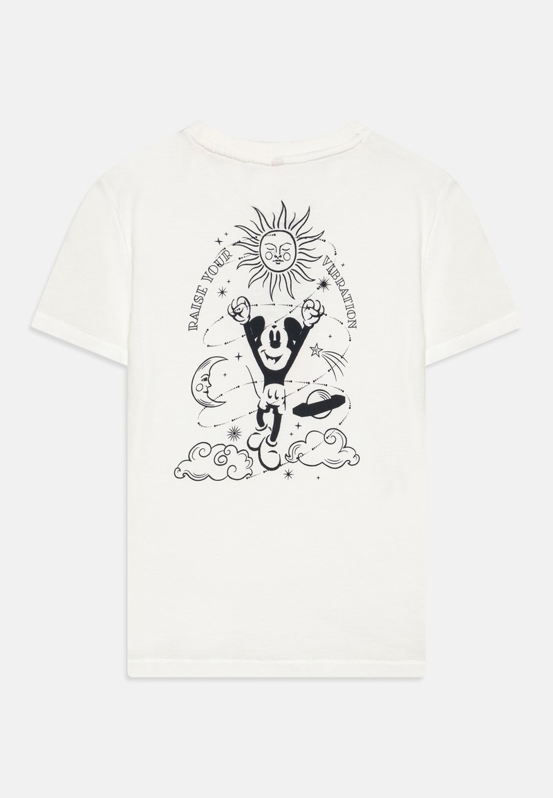 T-shirt en coton blanc avec un imprimé graphique noir représentant un personnage joyeux entouré d'éléments célestes et le texte "ÉLÈVE TA VIBRATION."