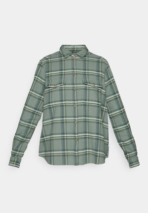 Groene geruite lange mouwen overhemd van zachte stof. Heeft twee borstzakken, knopen en contrasterende gele en blauwe strepen in het ruitpatroon.